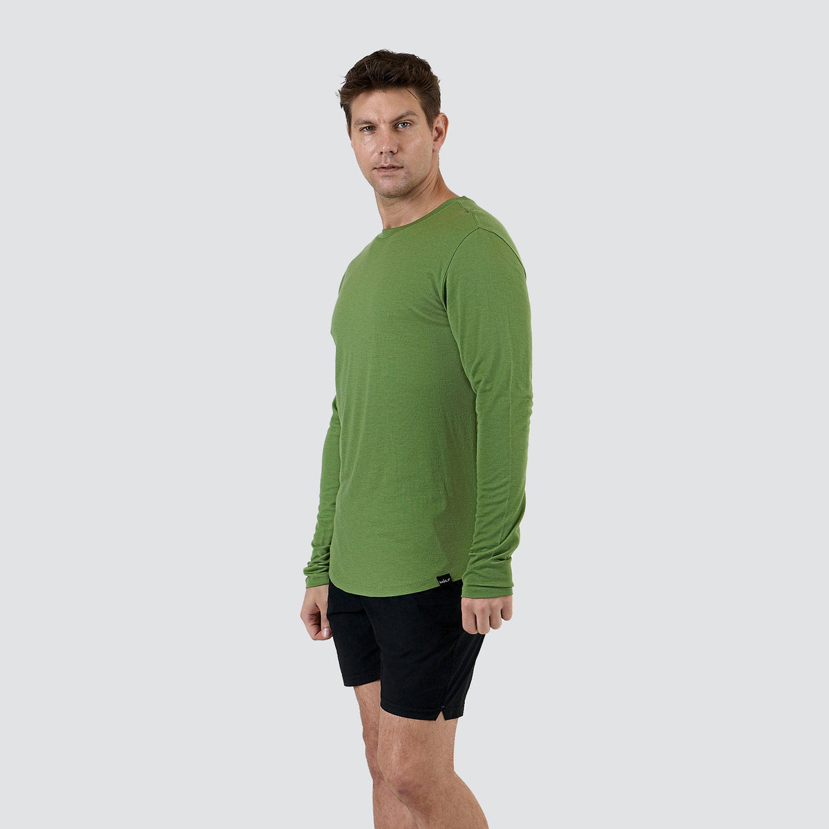 Men's ultralight merino wool long sleeve shirt in Forrest Moss, side view showing drop hem
